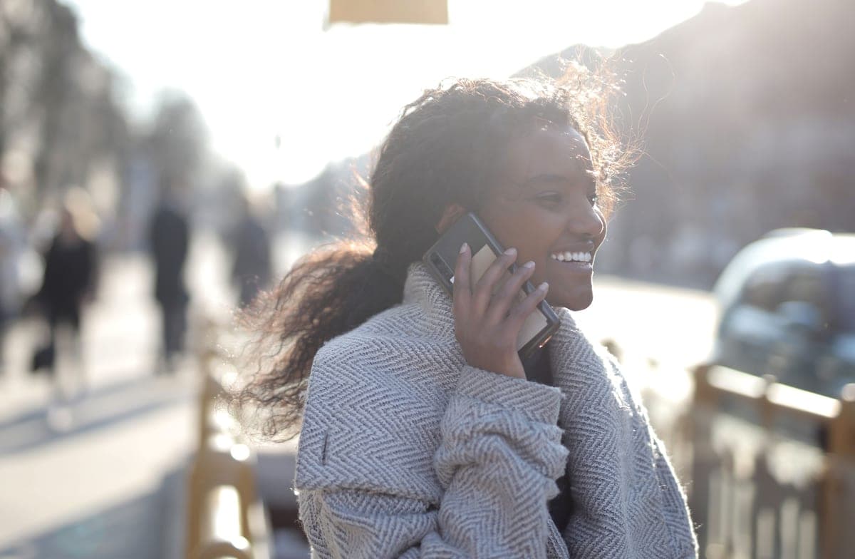 A young woman on a phone call while walking outside on a sunny day