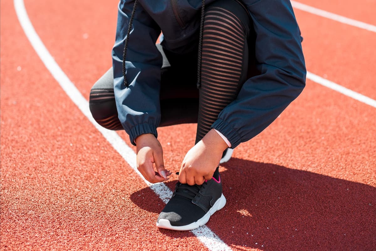 An athlete tying sneakers on a running track