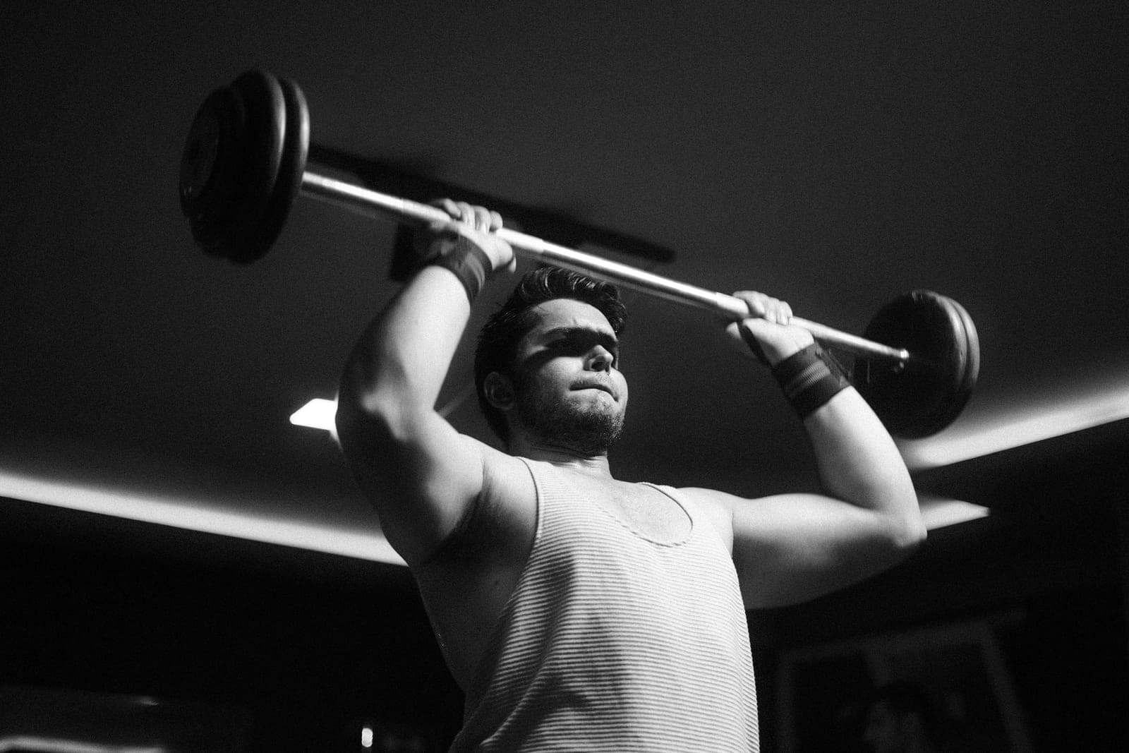 A black-and-white photo of a man lifting weights indoors